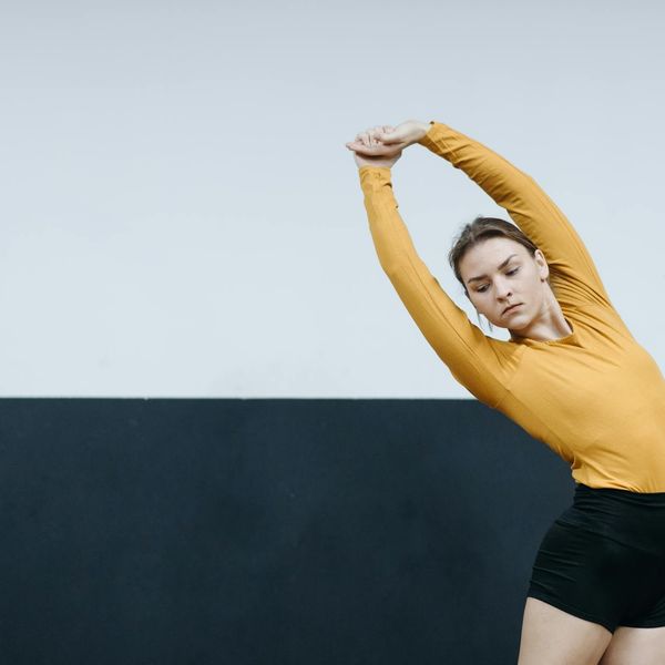 Person stretching gently in a bright, minimalist space.